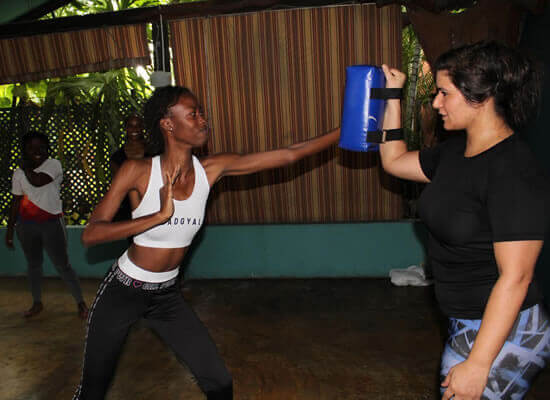 Photograph of a young woman punching a punching pad